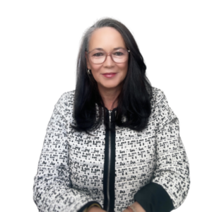 A professional portrait of a woman with long dark hair and glasses, wearing a stylish black and white patterned jacket. She is smiling warmly at the camera, exuding confidence and approachability. The background is plain, keeping the focus on her, and highlighting her poised and professional demeanour.