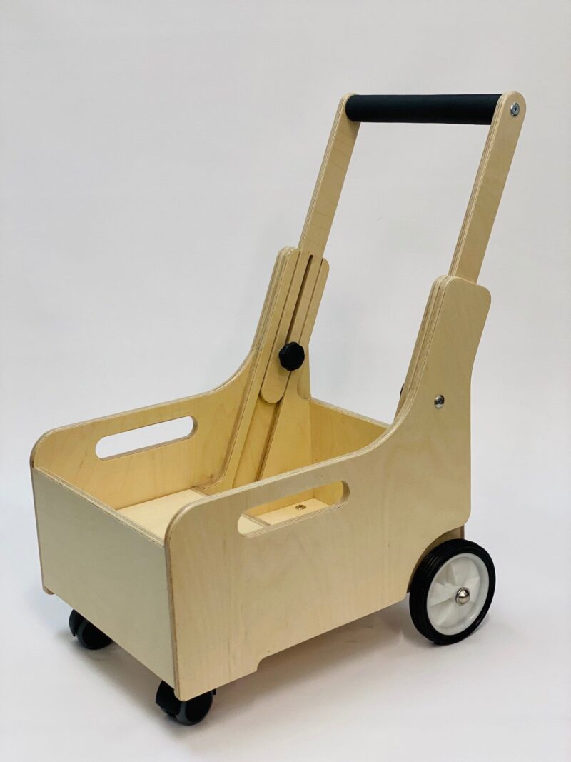 A wooden mobility aid cart with a sturdy rectangular box design, featuring cut-out handles on the sides for easy lifting. The cart has two larger wheels at the rear and two smaller wheels at the front, with a black cushioned handlebar for pushing