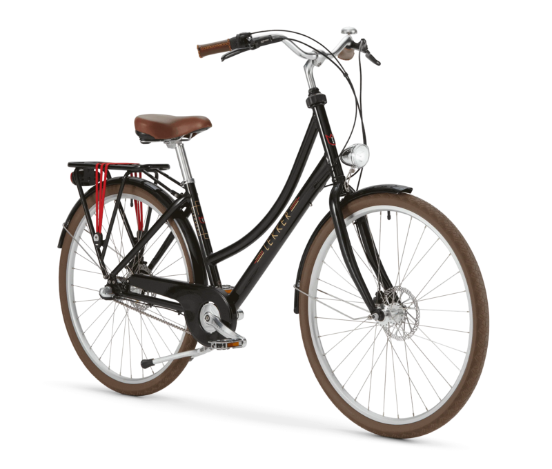 A black cruiser bicycle with a brown seat and brown handle grips. The bike has a rear cargo rack with red straps, a front light, and a step-through frame design. The brand name 'LEKKER' is displayed on the frame. The bike features large brown tires with white rims and a chain guard for added protection.