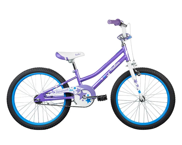 A child's bicycle with a purple frame and white accents. The bike features a white seat with purple details, purple handlebar grips, and blue rims. The frame and fork have star decorations, and the bike includes a kickstand and reflectors on the wheels for safety.